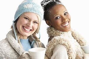 Two Young Women Wearing Warm Winter Clothes Holding Snowball In Studio