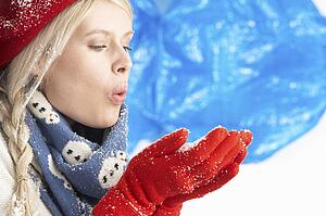 Young Woman Wearing Warm Winter Clothes And Hat Holding Snow In Studio