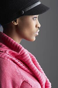 Fashionable Young Woman Wearing Cap And Knitwear In Studio