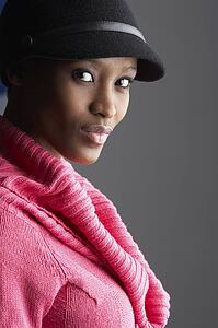 Fashionable Young Woman Wearing Cap And Knitwear In Studio