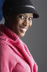 Fashionable Young Woman Wearing Cap And Knitwear In Studio