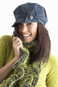 Fashionable Young WomanWearing Cap And Knitwear In Studio