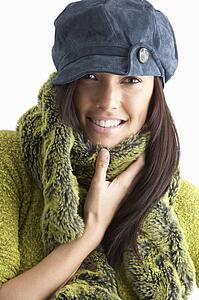 Fashionable Young WomanWearing Cap And Knitwear In Studio