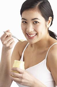 Young Woman Eating Yoghurt In Studio