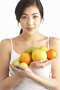 Young Woman Holding Citrus Fruit In Studio