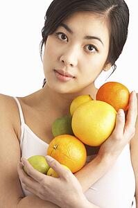 Young Woman Holding Citrus Fruit In Studio
