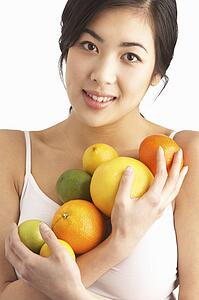 Young Woman Holding Citrus Fruit In Studio