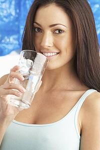 Young Woman Drinking Glass Of Water In Studio