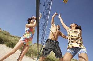 Group Of Teenage Friends Playing Volleyball On Beach