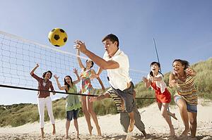 Group Of Teenage Friends Playing Volleyball On Beach