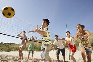 Group Of Teenage Friends Playing Volleyball On Beach