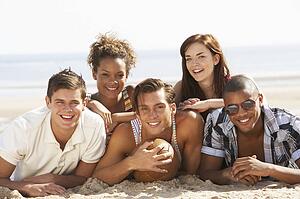 Group Of Friends Relaxing On Beach With Football Together
