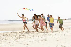 Group Of Friends Running Along Beach Together