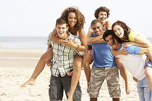 Group Of Friends Running Along Beach Together
