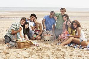 Group Of Friends Enjoying Barbeque On Beach Together