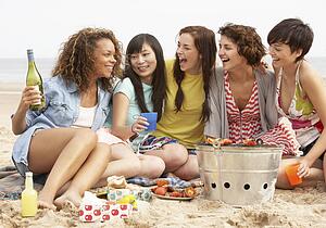 Group Of Girls Enjoying Barbeque On Beach Together