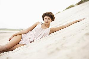 Fashionably Dressed Attractive Young Woman Laying Amongst Sand Dunes