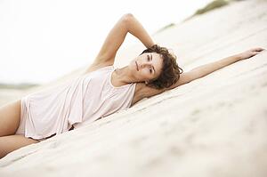 Fashionably Dressed Attractive Young Woman Laying Amongst Sand Dunes