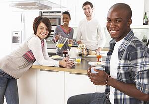 Group Of Young Friends Preparing Breakfast In Modern Kitchen