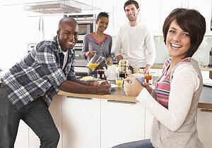 Group Of Young Friends Preparing Breakfast In Modern Kitchen
