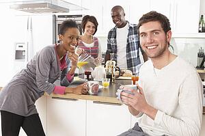 Group Of Young Friends Preparing Breakfast In Modern Kitchen