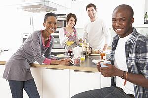 Group Of Young Friends Preparing Breakfast In Modern Kitchen