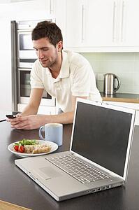 Young Man With Laptop In Modern Kitchen About To Eat Meal