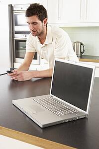 Young Man With Laptop In Modern Kitchen 