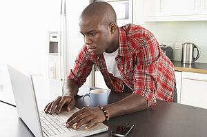 Young Man Using Laptop In Modern Kitchen 