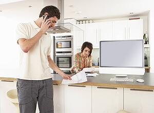 Young Couple Discussing Personal Finances In Modern Kitchen 