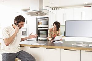 Young Couple Discussing Personal Finances In Modern Kitchen 