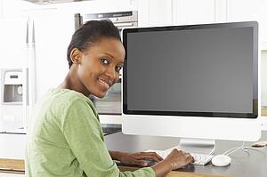 Young Woman Using Computer In Modern Kitchen 