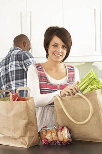 Young Couple Unpacking Shopping In Modern Kitchen 