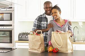 Young Couple Unpacking Shopping In Modern Kitchen 