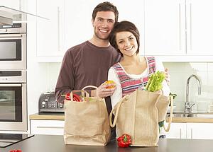 Young Couple Unpacking Shopping In Modern Kitchen 