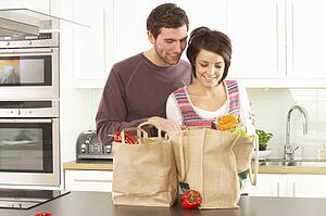 Young Couple Unpacking Shopping In Modern Kitchen 