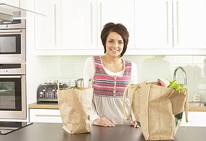 Young Woman Unpacking Shopping In Modern Kitchen