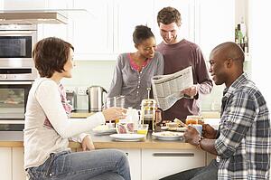 Group Of Young Friends Preparing Breakfast In Modern Kitchen