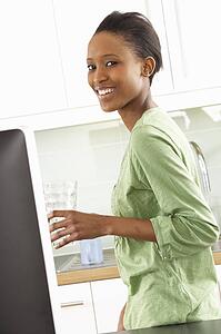 Young Woman Using Computer In Modern Kitchen 