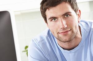 Young Man Using Computer In Modern Kitchen 