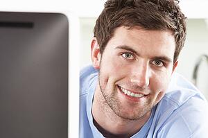 Young Man Using Computer In Modern Kitchen 