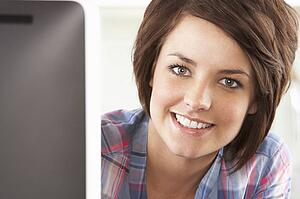 Young Woman Using Computer In Modern Kitchen 