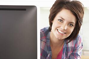 Young Woman Using Computer In Modern Kitchen 