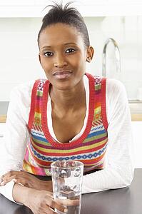 Young Woman Drinking Glass Of Water In Modern Kitchen 