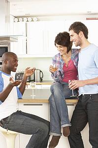 Group Of Young Friends Enjoying Glass Of Wine In Modern Kitchen