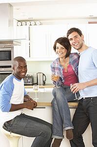 Group Of Young Friends Enjoying Glass Of Wine In Modern Kitchen