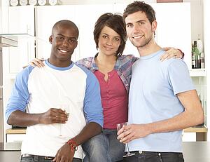 Group Of Young Friends Enjoying Glass Of Wine In Modern Kitchen
