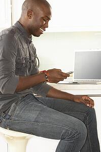 Young Man Relaxing Sitting In Kitchen Talking On Phone