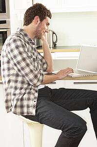 Young Man Relaxing Sitting In Kitchen Talking On Phone