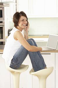 Young Woman Relaxing Sitting In Kitchen Talking On Phone